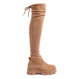 Kvinders lårhøje støvler på en beige platform