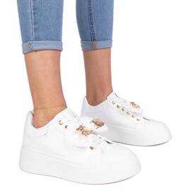 Hvide sneakers dekoreret med en bue og en gylden bamse