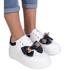 Sorte sneakers dekoreret med en bue og en gylden bamse