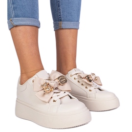 Beige sneakers dekoreret med en bue og en gylden bamse