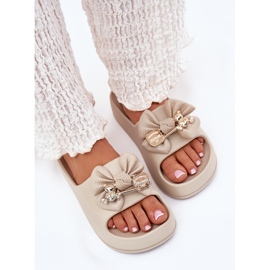Kvinders skum flip flops på platformen med en bue og en mørk beige broche